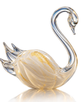A decorative crystal swan figurine with a curved neck, featuring a milky white body with gold glitter accents and a clear glass beak and tail, set against a plain white background with a soft reflection below.