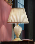 A Venetian cream colour glass table lamp with fabric shade on a round coffee table in a modern contemporary luxury interiors