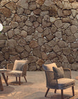 Outdoor seating area with stone wall and round tables.
