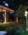 Modern outdoor garden light fixture in a residential setting with a house and garden.