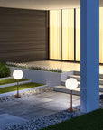 Modern outdoor setting with two spherical garden lights on a stone path.