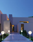 Modern house exterior with illuminated steps and spherical floor lamps at dusk.