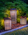 Three illuminated outdoor solar lanterns in a garden setting