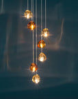 Terzani Mizu Pendant Light in a cluster with champagne and cognac finish on a blue coloured wall.