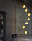Terzani Mizu Pendant Italian crystal light in a cluster of 7 pcs in gold dust finish above a corner table. Available at Spacio in India.
