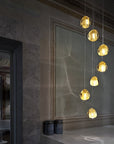 Terzani Mizu Pendant Italian crystal light in a cluster of 7 pcs in gold dust finish above a corner table. Available at Spacio in India.