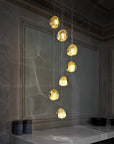 Terzani Mizu Pendant Italian crystal light in a cluster of 7 pcs in gold dust finish above a corner table. Available at Spacio in India.