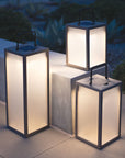Three illuminated outdoor lanterns on a patio at night by Les Jardins available at Spacio retail stores in Mumbai & Kolkata.