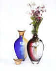 Two colourful sculptural vases from Utopia & Utility with one containing flowers on a white background, available at Spacio retail stores in Mumbai & Kolkata.