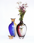 Two colorful vases with one containing flowers on a white background