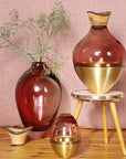 Decorative vases with gold accents on a wooden surface against a pink checkered background