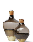 Two glass sculptural vases with wood top on a white background