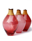 Three glass sculptural vases with wood accents on a white background