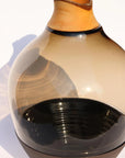 Sculptural Glass Vase with a wooden top and black base on a white background from Utopia & Utility, available at Spacio retail stores in Mumbai.