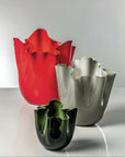 Three colorful venini murano vases (red, silver, green) on a reflective surface with a light gray background at Spacio retail store in Mumbai