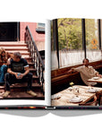 Assouline New York Chic coffee table book displaying photos of Creative director Demet Müftüoglu-Eseli with director Alphan Eseli on the stairs & seating in a restaurant on white back ground available at Spacio India for luxury home decor accessories collection of Travel Coffee Table Books.