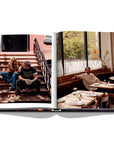 Assouline New York Chic coffee table book displaying photos of Creative director Demet Müftüoglu-Eseli with director Alphan Eseli on the stairs & seating in a restaurant on white back ground available at Spacio India for luxury home decor accessories collection of Travel Coffee Table Books.