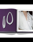 Assouline Boghossian: Expertise Craftsmanship Innovation coffee table book displaying photo of Boghossian Merveilles Halo 18k White Gold Diamond Extra Large Earrings & it wored on white dress as fashion on white background at Spacio India for luxury home decor collection of Jewellery Coffee Table Books.