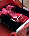 Assouline Dior by John Galliano coffee table book on a red coffee table in a modern interior available at Spacio India for luxury home decor collection of Fashion Coffee Table Books.
