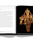 Assouline Dior by John Galliano coffee table book displaying photo of Spring-Summer 2004 Haute Couture Golden Dress collection on a white back ground available at Spacio India for luxury home decor collection of Fashion Coffee Table Books.