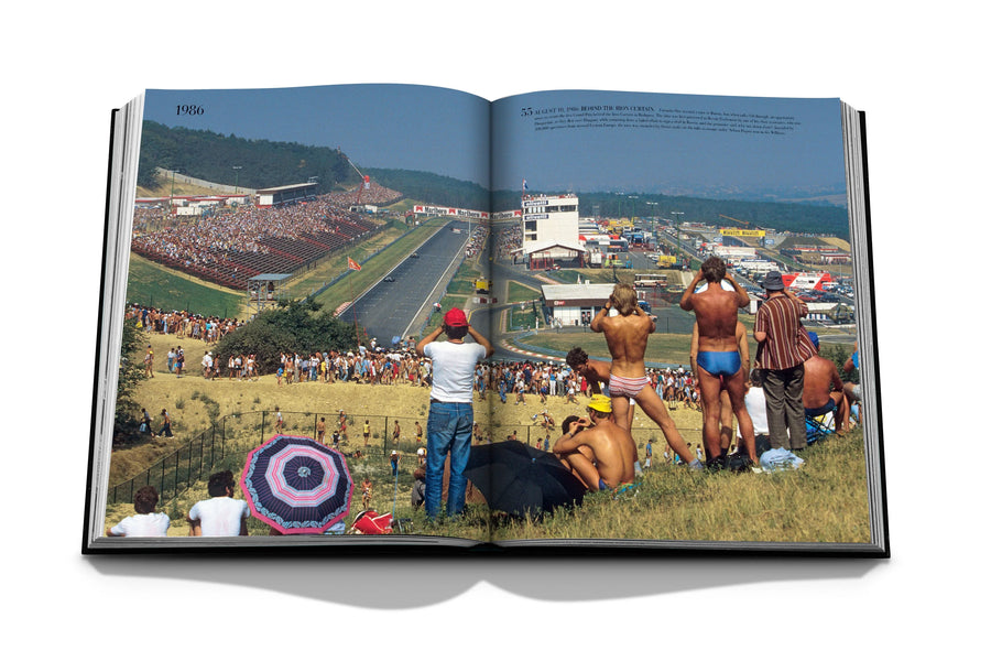 Assouline Formula 1: The Impossible Collection coffee table book people watching race in 1986 from a distance on a white back ground available at Spacio India for luxury home decor collection of Ultimate & Sports Coffee Table Books.