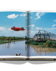 Assouline James Bond: Destinations coffee table book displaying photo from The Man with the Golden Gun film , Red car action scene on a white background available at Spacio India for luxury home decor accessories collection of Travel Coffee Table Books.