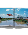 Assouline James Bond: Destinations coffee table book displaying photo from The Man with the Golden Gun film , Red car action scene on a white background available at Spacio India for luxury home decor accessories collection of Travel Coffee Table Books.