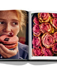 Assouline Paris Chic coffee table book displaying photos of Roses & a girl eating donut in Paris on white back ground available at Spacio India for luxury home decor accessories collection of Travel Coffee Table Books.