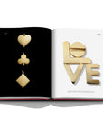 Assouline Cipullo: Making Jewelry Modern coffee table book displaying Cards symbols & Spelling L-O-V-E in 24 Gold caret on a coffe table available at Spacio India for luxury home decor collection of Jewellery Coffee Table Books.