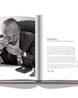 Assouline G Glenn: Spiro the art of a jewel coffee table book displaying photo of Glenn Spiro checking details of diamond on a white back ground available at Spacio India for luxury home decor collection of Jewellery Coffee Table Books.