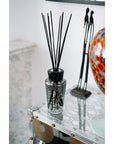 Baobab Black Pearls diffuser in a glass vase on a table.