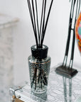 Baobab Black Pearls diffuser in a glass vase on a table.