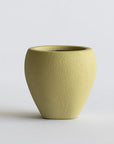 Green ceramic vase on a light gray background