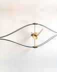 A Nomon handcrafted wall clock made of brass and wood with a creative eye shape, the Clock Nomon Look Mini Gold Walnut Arms MLON000N.