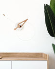 Wooden desk with a clock and plant against a white wall