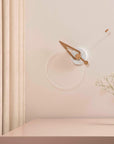 Minimalist wall clock on a light pink wall with a vase of flowers on a matching surface.