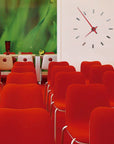Nomon Spain Tacon L 12 Red on a white wall behind red chairs of auditorium available at Spacio India for luxury home decor collection of Timepieces & Clocks.