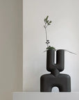 A 101 Copenhagen hand glazed vase with a quirky plant on top, perfect for an interior setting.