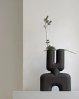 A 101 Copenhagen hand glazed vase with a quirky plant on top, perfect for an interior setting.