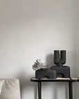 A 101Cph Cobra Double Medio Coffee 211037 vase in the brand of 101 Copenhagen sits on a table in a quirky living room interior setting.