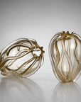 Two decorative glass sculptures with organic, flowing ribbed forms, one lying down and one standing upright, in a smoky translucent amber-brown glass against a light gray gradient background.