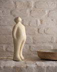 A Gardeco Ceramic Sculpture Visitor Plus Beige Cor46, featuring a beige finish, depicts a man standing next to a bowl.