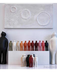 A group of Gardeco Ceramic Sculpture Visitor Plus Sand Cor02 sculptures in front of a painting with a sand finish.