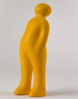 An art sculpture of a yellow figure standing on a white background, the Gardeco Ceramic Sculpture Visitor Plus Yellow Acafrao Clear Cor36.