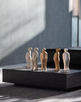 A collection of Gardeco Ceramic Sculpture Visitor Small Taupe Cor27 figurines, crafted by a Belgian sculptor, displayed on a sleek black table.