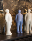 A group of Gardeco Ceramic Sculpture Visitor Plus Sand Cor02 figurines with a sand finish on a table next to a painting.