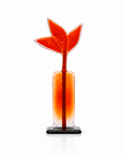 A decorative glass sculpture featuring a stylized red-orange arrowhead or leaf-like top mounted on a rectangular glass stem, set in a clear cylindrical base with a small black square pedestal, photographed on a clean white background.