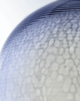 A blue and white Italamp Muna pendant product illuminated with lighting, placed on a white surface.