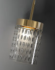 Modern pendant light with gold fixture and textured glass shade on a gray background