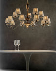 A table with a glass of wine and a Lorenzon Divina Chandelier emanating timeless elegance through its Italian craftsmanship.